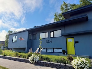 A modern building with a number '804' on the facade, a yellow door, and an American flag. - Lovely 2-bedroom apartment in Anchorage perfect for your getaway (Anchorage)