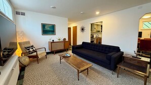 A living room with a sofa, armchairs, a coffee table, and a TV. There is a kitchen visible in the background. - Lovely 2-bedroom apartment in Anchorage perfect for your getaway (Anchorage)