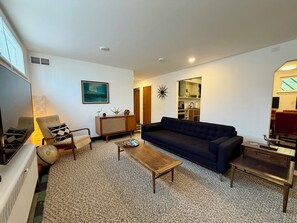 A living room with a sofa, armchairs, a coffee table, and a TV. There is a kitchen visible in the background. - Lovely 2-bedroom apartment in Anchorage perfect for your getaway (Anchorage)
