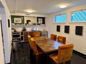 A dining area with a wooden table, four chairs, a coffee machine, and a kitchen in the background. - Lovely 2-bedroom apartment in Anchorage perfect for your getaway (Anchorage)