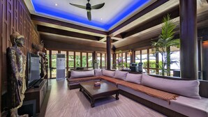 A spacious living area with a large sectional sofa, a flat-screen TV, and a ceiling fan. - Nakawanna Villa (Tambon Kamala)