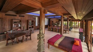 A spacious room with a large bed, wooden furniture, and a dining area. - Nakawanna Villa (Tambon Kamala)