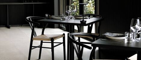 A restaurant interior with a bar area, dining tables, chairs, and a view of greenery outside.