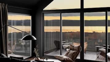 A modern living room with a large window, a sofa, a chair, and a table.