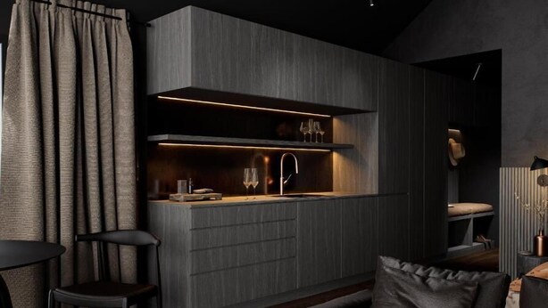 Una cocina moderna con electrodomésticos integrados, una barra y una zona de estar con sofá y sillones.