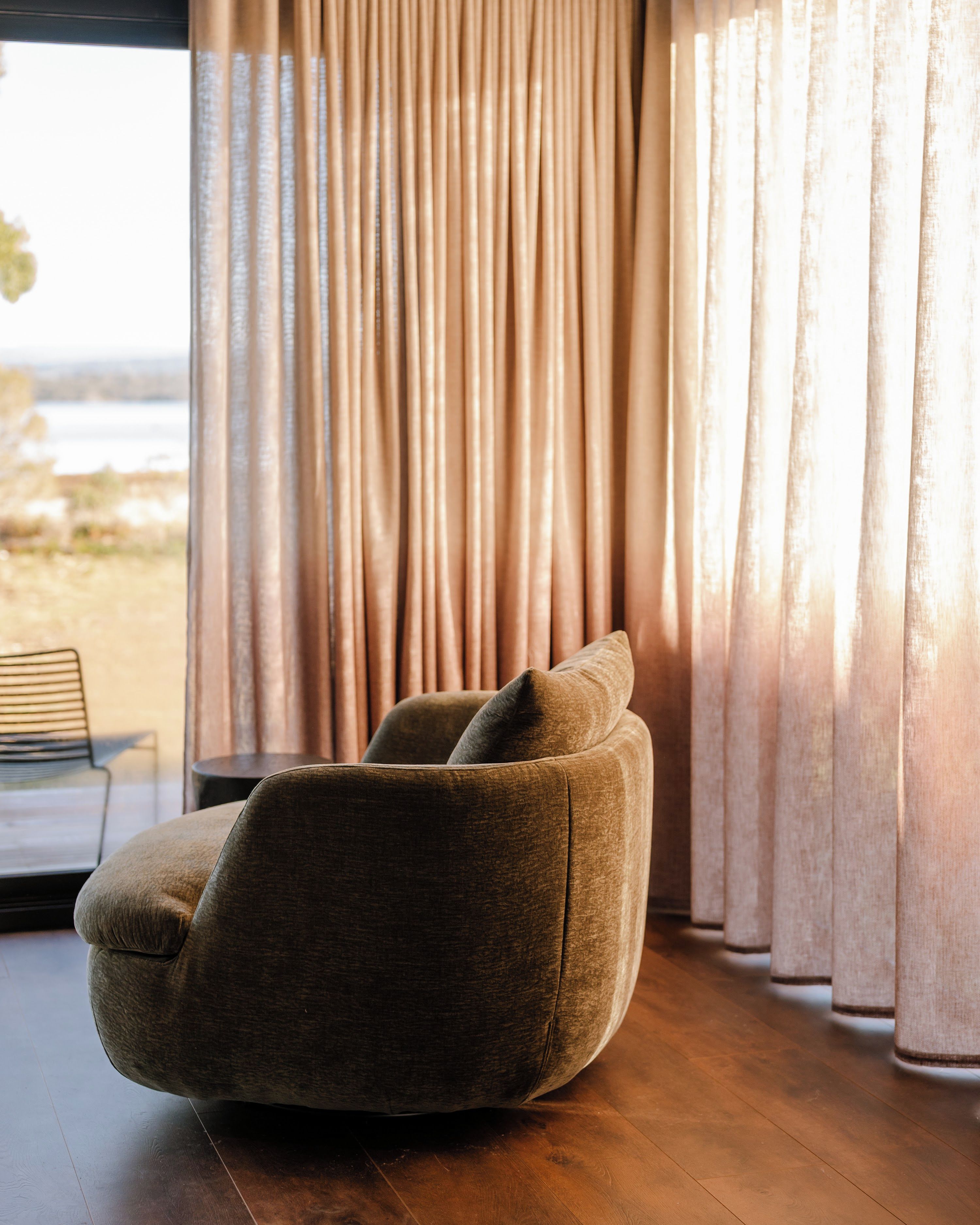 A modern living room with a large window, a plush sofa, and a view of the outdoors.