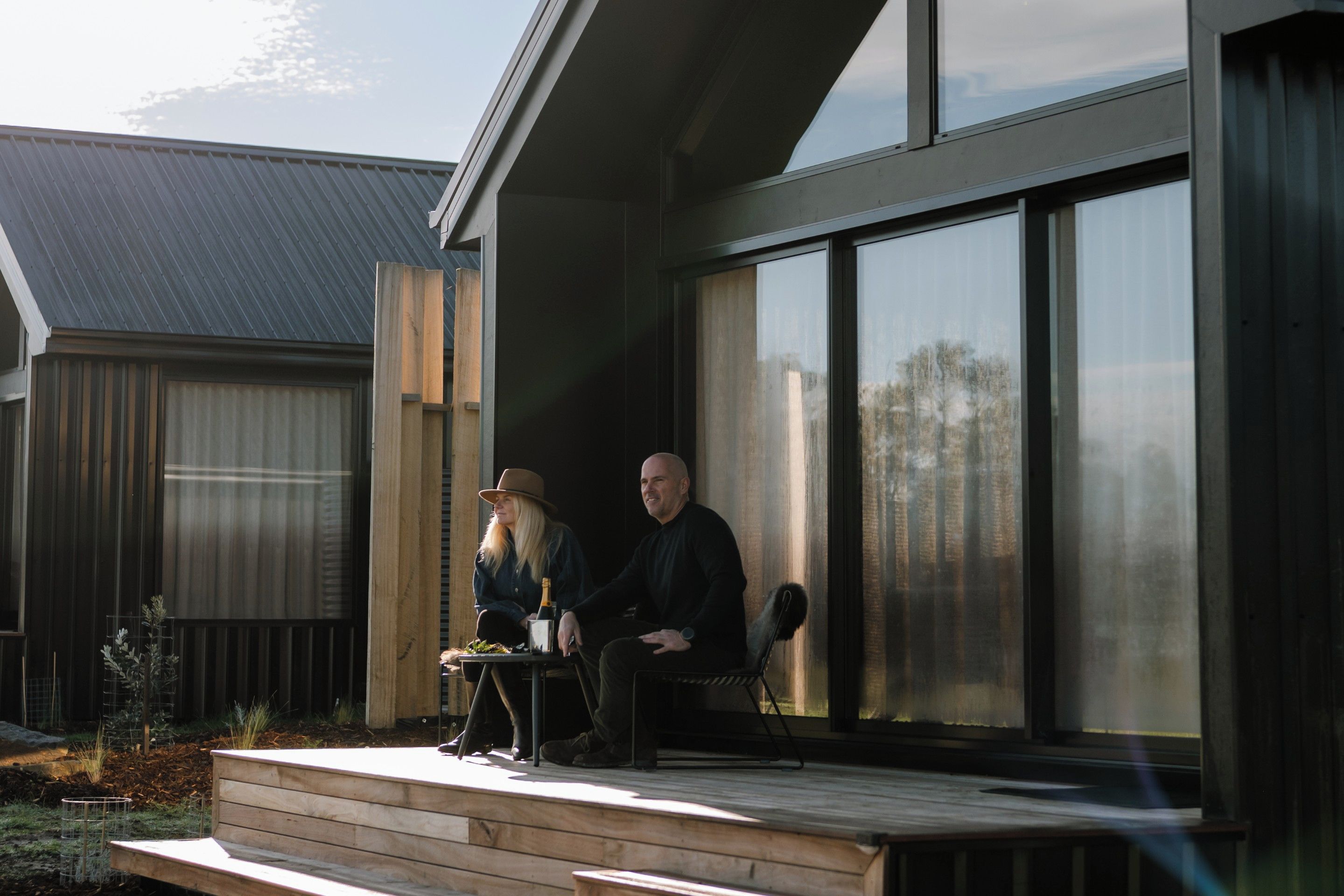 A modern house with a large glass window, a wooden deck, and a metal railing.