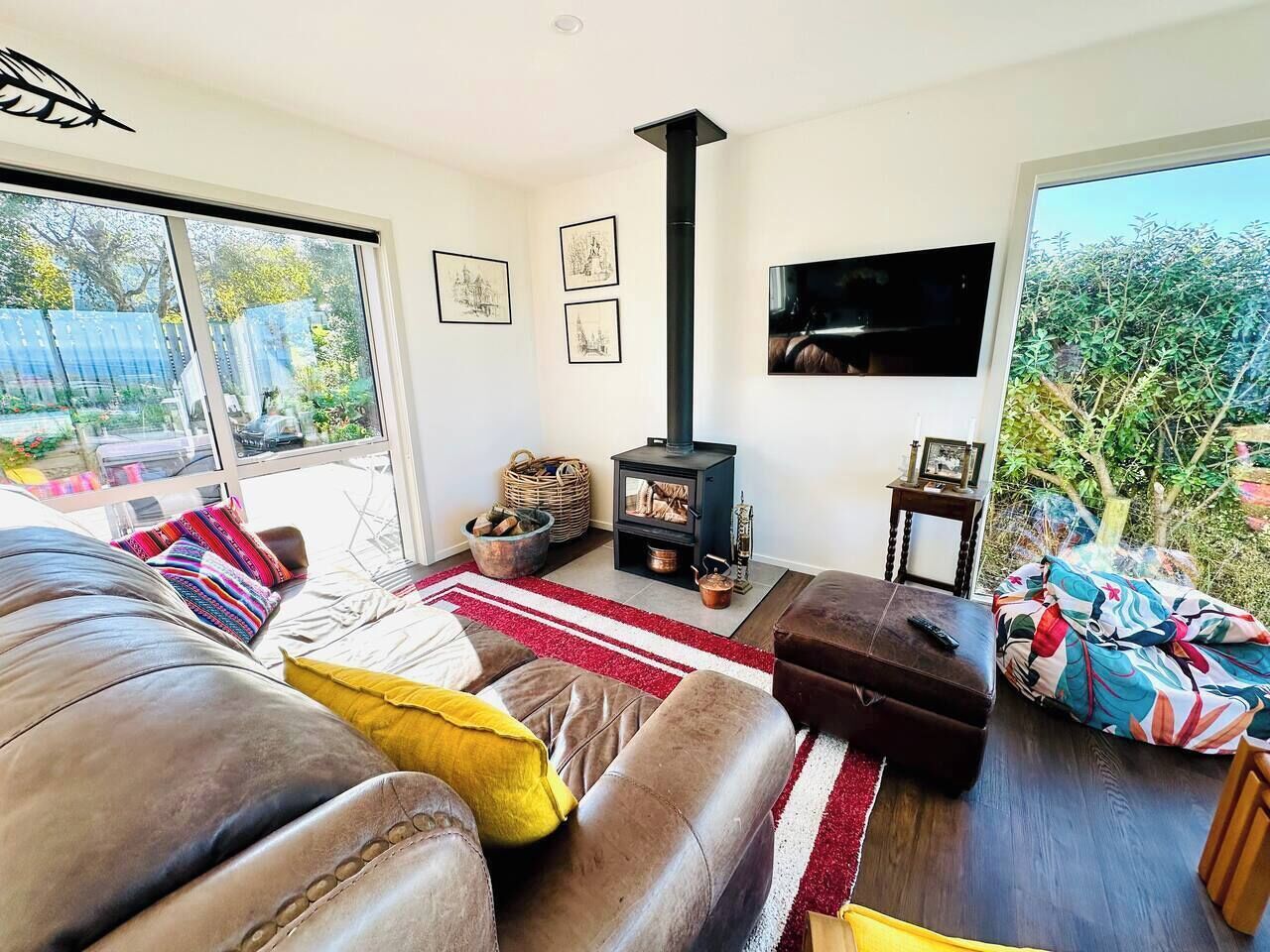 A modern living room with a fireplace, leather sofas, and a large window overlooking a garden.