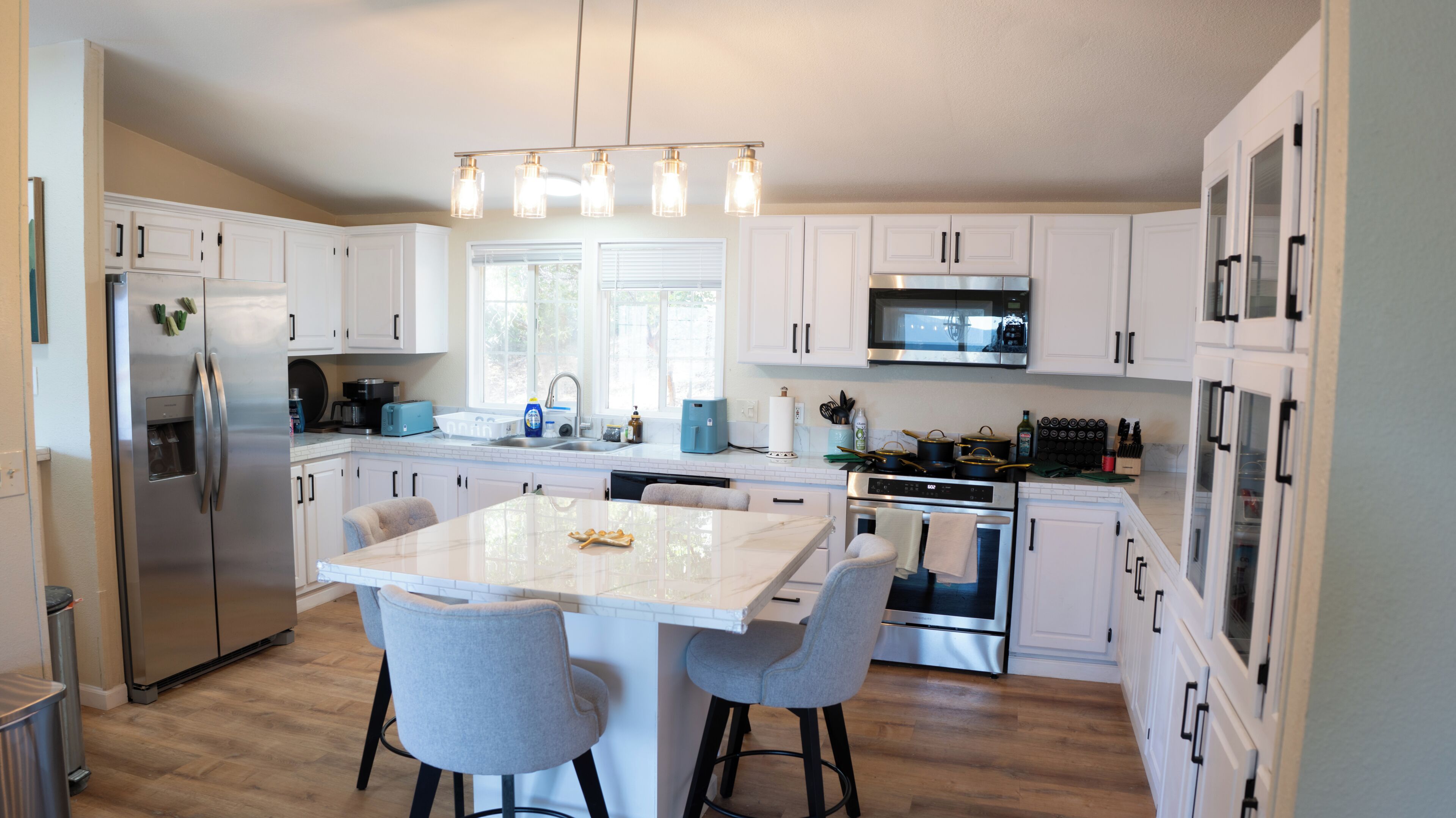 A modern kitchen with white cabinets, stainless steel appliances, and a central island with bar stools.