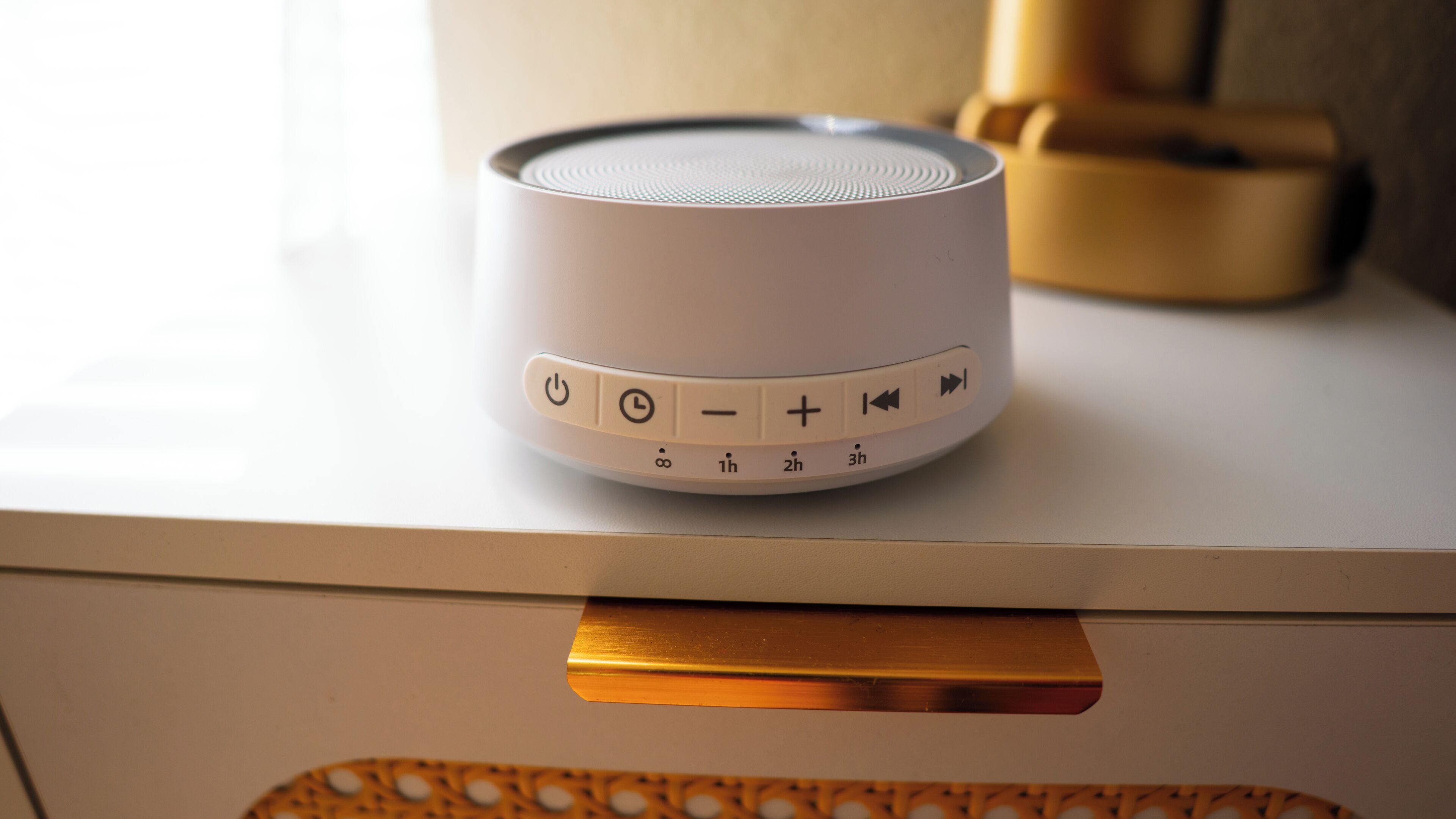 A white speaker with control buttons on a white surface.