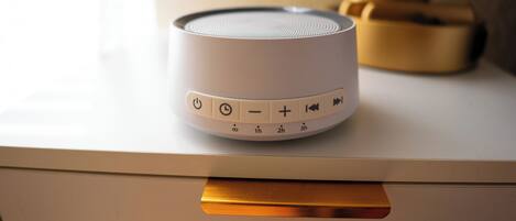 A white speaker with control buttons on a white surface.