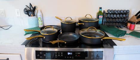 Una cocina con estufa, ollas, sartenes y un reloj digital que marca las 5:41.