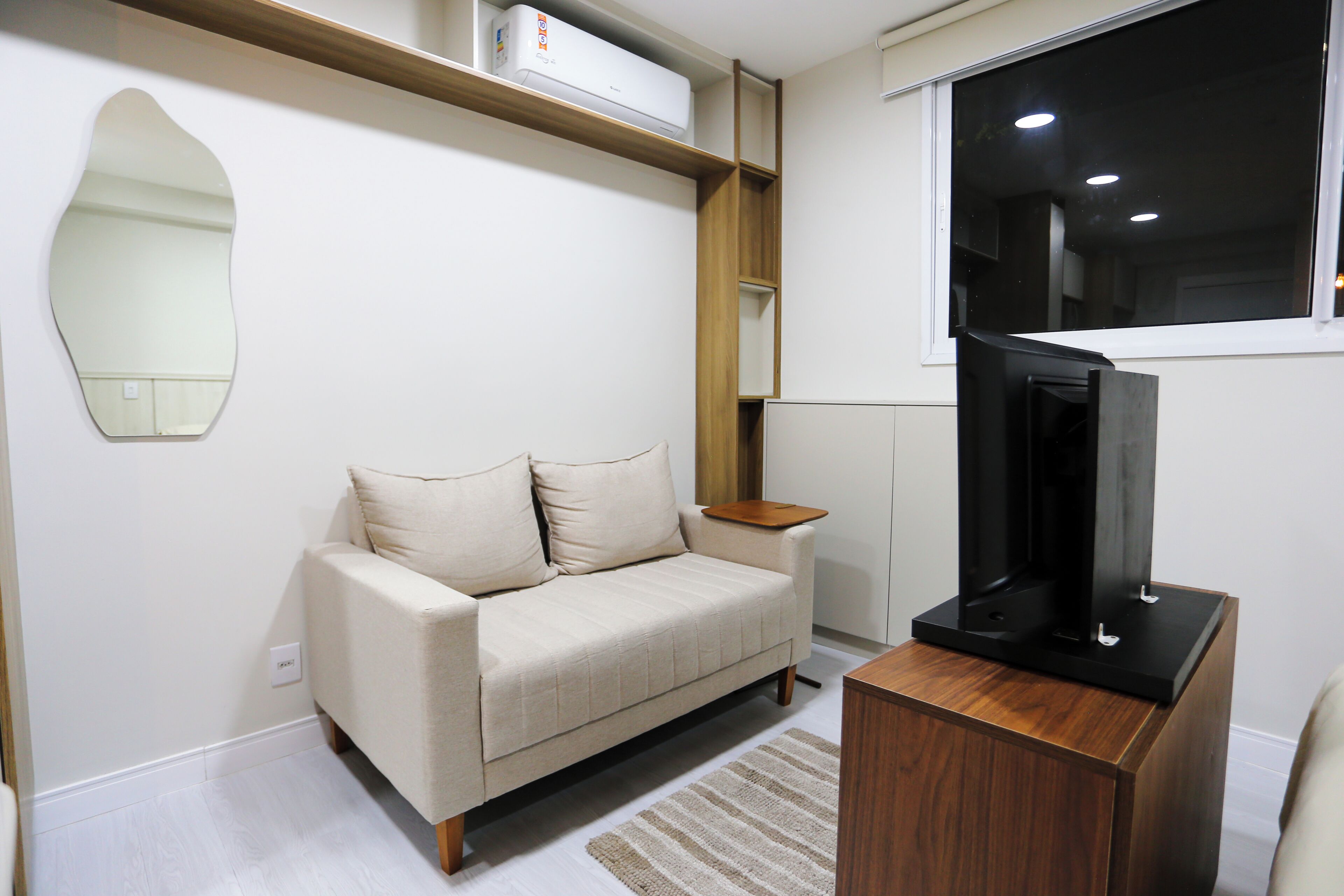 A modern living room with a sofa, a flat-screen TV, and a wooden side table.