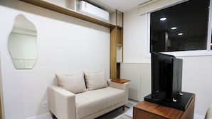 Ein stilvolles Wohnzimmer mit einer Couch, einem Flachbildfernseher und einem Holztisch.