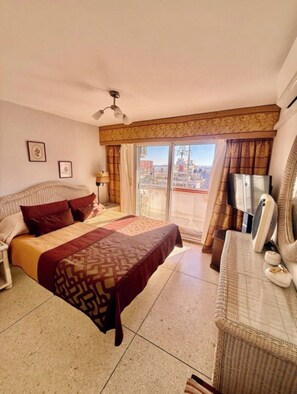 A hotel room with a bed, a sofa, a TV, and a balcony with a city view. - 2-bedroom apartment in fabulous Punta del Este with AC and gym (Punta del Este)