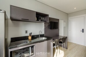 A modern kitchen with a built-in stove, sink, and microwave. There is a dining area with a table and chairs. - Studio w/ Pool Close to Ccmq Tco1008 (Porto Alegre)