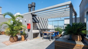 En utomhusplats med en pergola, sittplatser och krukväxter.