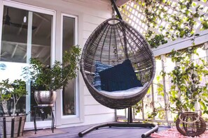 A hanging chair with a cushion, a potted plant, and a patio area with a wooden deck. - Entire home: Residential home in Rio Hondo, Texas, United States. (Rio Hondo)