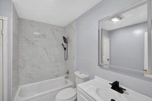 A bathroom with a bathtub, toilet, and sink.