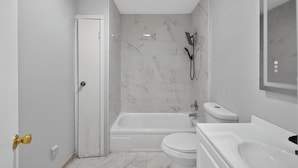 Et moderne badeværelse med badekar, toilet og bruser.