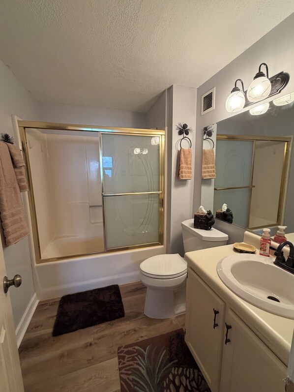 A bathroom with a glass-enclosed shower, a toilet, a sink with a mirror, and a towel rack.
