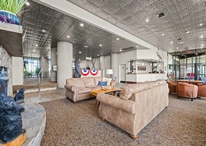Eine geräumige Lobby mit hoher Decke, einem Empfangsbereich und einer Sitzecke mit Sofas.