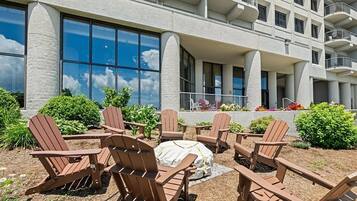 A hotel with outdoor seating area featuring Adirondack chairs and a covered picnic table.