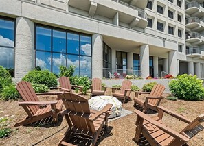 A hotel with outdoor seating area featuring Adirondack chairs and a covered picnic table.