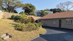 A residential area with a paved driveway leading to a house with a tiled roof. - Room-nombelas Cottage (Westville)