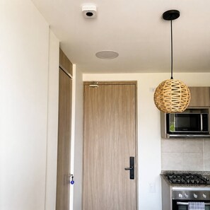 A modern kitchen with a microwave, stove, and hanging light fixture. - Ocean View 14th Floor Pools & Beach (Santa Marta)