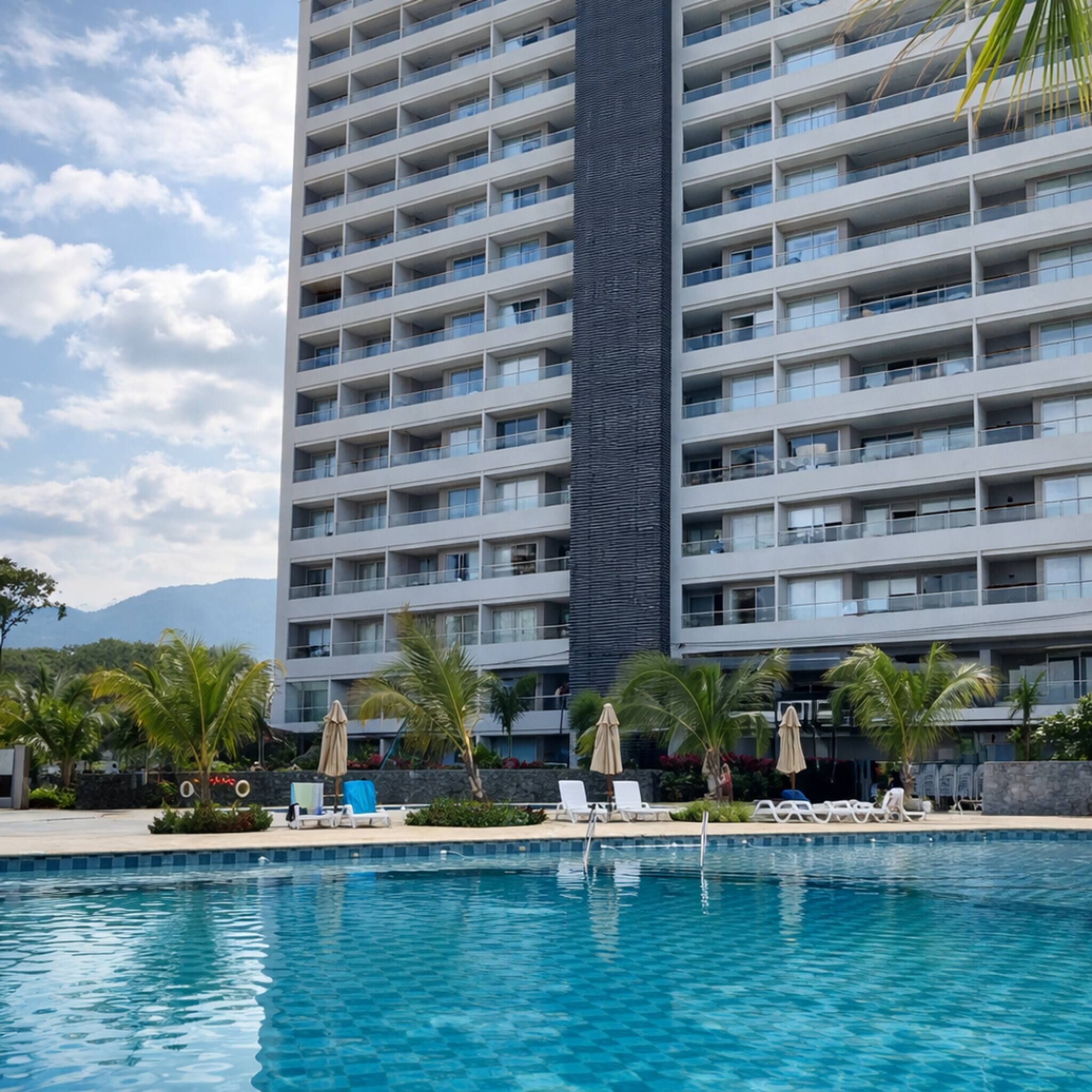 Ein Hochhaus-Hotel mit Pool und Liegestühlen.