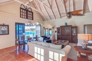 A spacious living area with a high ceiling, a dining area with a view, and a cozy seating area.