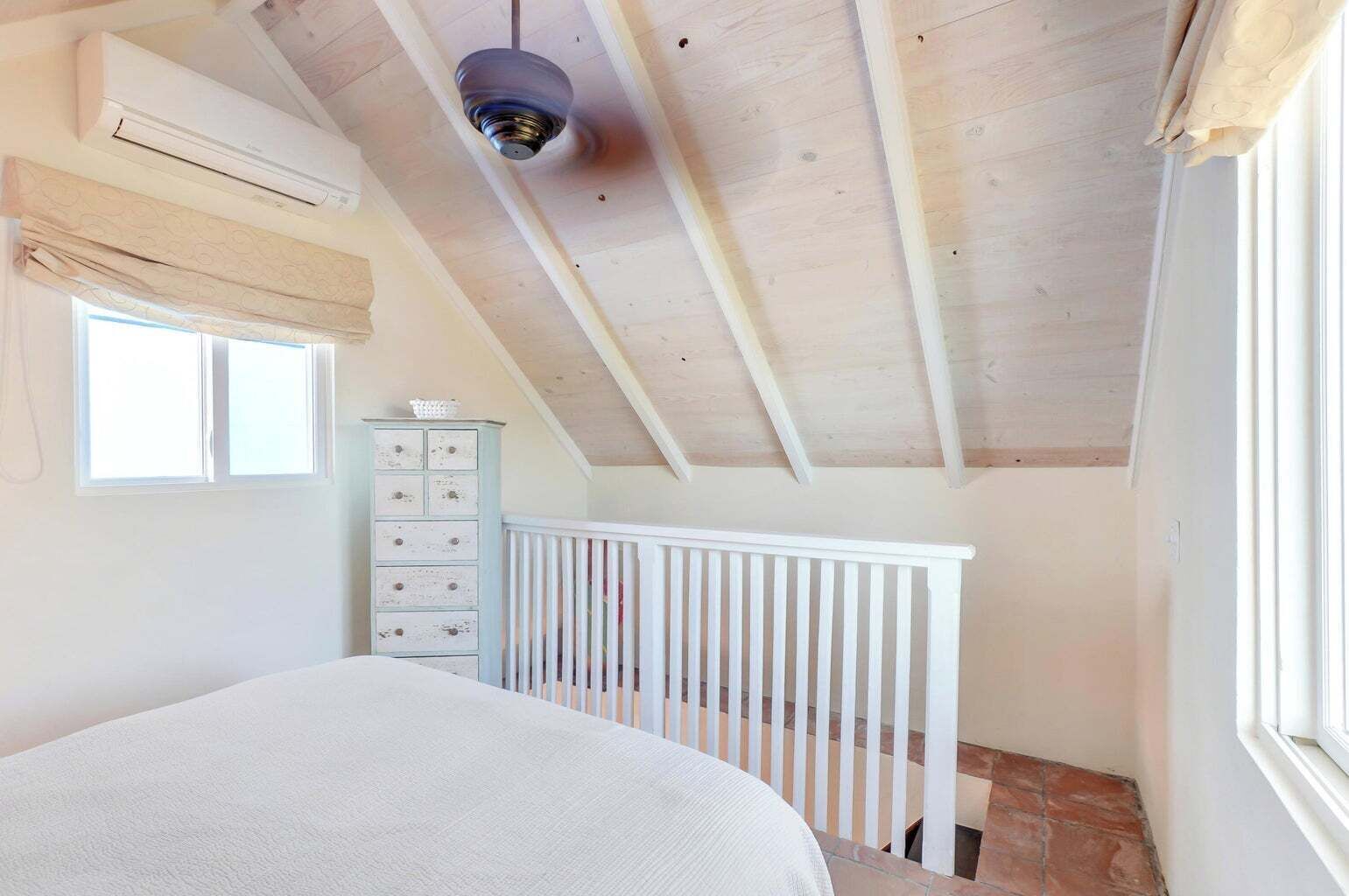 Un dormitorio con cama, cómoda, ventana y ventilador de techo.