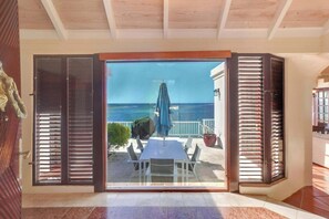 Una habitación con puerta corrediza de vidrio que da a un balcón con vista al mar.