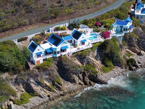 A coastal property with multiple buildings, a road, and a rocky shoreline.