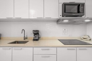 Eine Küche mit weißen Schränken, einer eingebauten Mikrowelle, einer Kaffeemaschine und einem Spülbecken.
