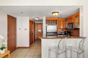 Eine Küche mit Holzausstattung, einem Edelstahlkühlschrank, einer Mikrowelle und einer Arbeitsplatte aus Granit.