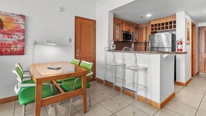 Een moderne keuken met een centraal kookeiland, barstoelen en een eettafel met stoelen.
