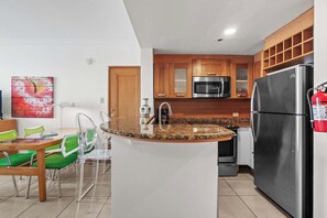 A modern kitchen with a granite countertop, stainless steel appliances, and wooden cabinets. - Lagoon Front 3BR - Balconies & Pool (San Juan)