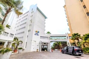 A hotel entrance with a modern design, featuring a prominent logo on the facade. - Lagoon Front 3BR - Balconies & Pool (San Juan)