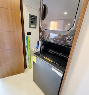 Eine kompakte Küche mit integriertem Backofen und einer Mikrowelle, einer kleinen Arbeitsfläche und einem Holzkasten.