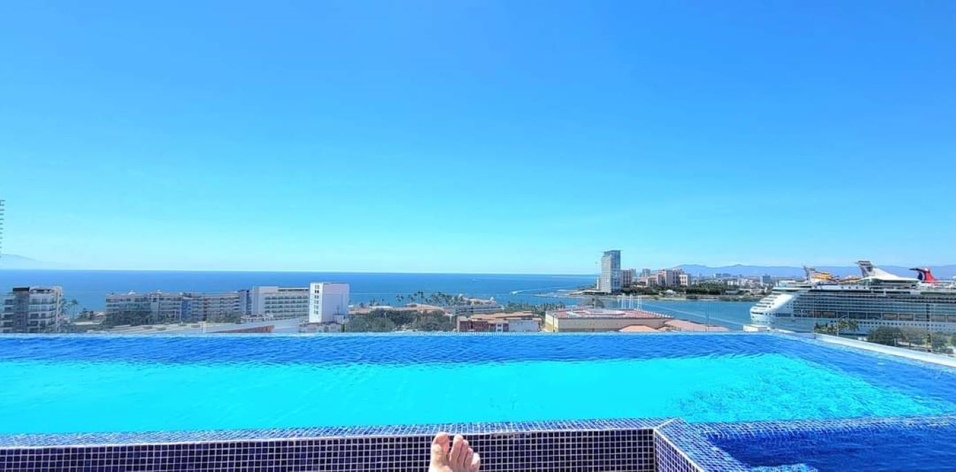 A swimming pool with a view of the ocean and a cruise ship in the distance.
