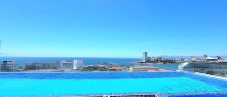 A swimming pool with a view of the ocean and a cruise ship in the distance.