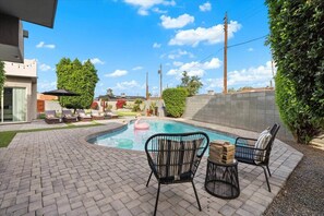 A backyard with a swimming pool, lounge chairs, and a flamingo float. - Two Homes Together | Great For Groups! (Scottsdale)