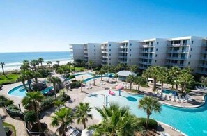 Ein Resort mit Poolbereich, Palmen und Meerblick.
