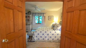 A bedroom with a bed, a ceiling fan, a window with curtains, a bookshelf, and a bedside lamp. - 3BR Birchwood Pines in Harbor Springs with WiFi, and fireplace. (Harbor Springs)