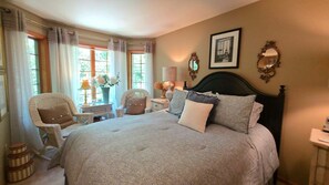 A bedroom with a large bed, two chairs, a nightstand, and a window with curtains. - 3BR Birchwood Pines in Harbor Springs with WiFi, and fireplace. (Harbor Springs)