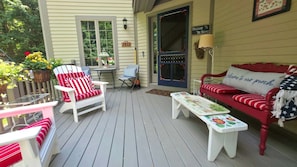 A porch with a red and white striped sofa, a white armchair, and a small table with a floral tablecloth. - 3BR Birchwood Pines in Harbor Springs with WiFi, and fireplace. (Harbor Springs)