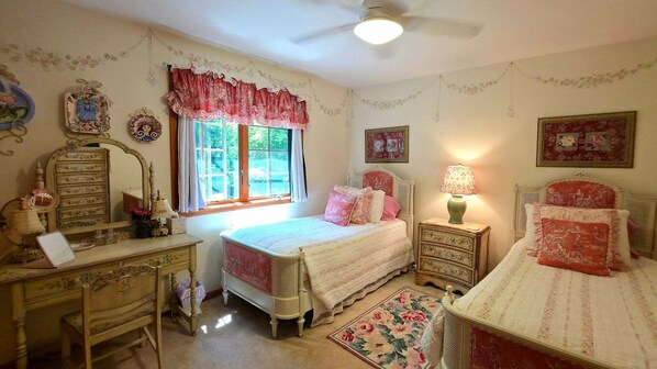 Quarto com duas camas, uma cômoda, uma mesa de vaidade e uma janela com cortinas.