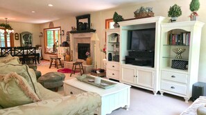 Ein gemütliches Wohnzimmer mit Kamin, Fernseher und Bücherregal.